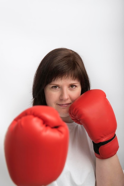 Portret van zelfverzekerde jonge vrouw in bokshandschoenen op witte achtergrond. feminisme. vrouw vecht voor gerechtigheid.