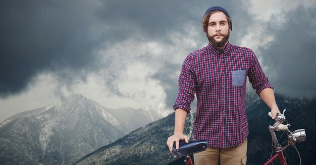 Portret van zelfverzekerde mannelijke reiziger die een fiets op de berg houdt