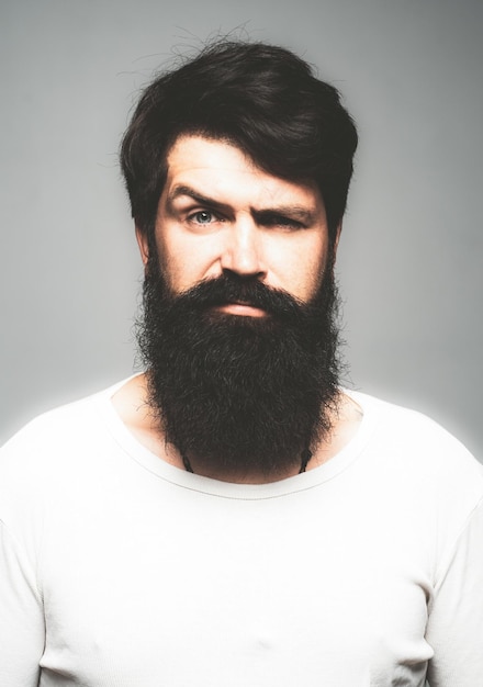 Foto portret van zelfverzekerde serieuze man heeft baard en snor ziet er serieus geïsoleerd hipster man modellen in studio zakenman denken knappe man met baard snor en trendy kapsel