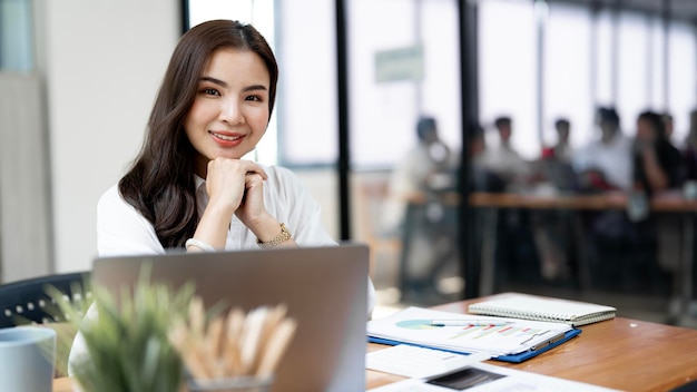 Portret van zelfverzekerde zakenvrouw met collega's in bestuurskamer Poseren zittend aan een bureau