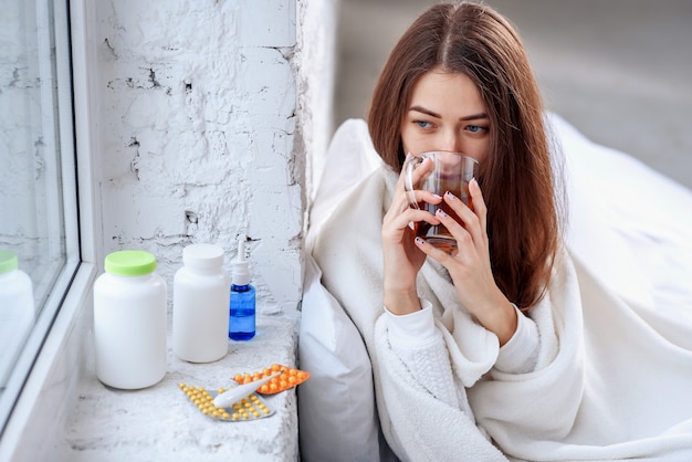 Portret van ziek ongezond meisje die verwarmende drank binnen drinken