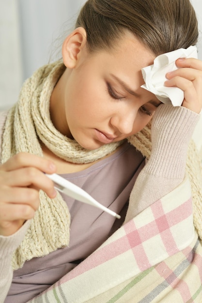 Foto portret van zieke jonge vrouw met thermometer