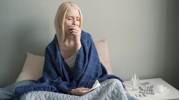 Foto portret van zieke vrouw thuis. jonge vrouw hoesten in de slaapkamer.