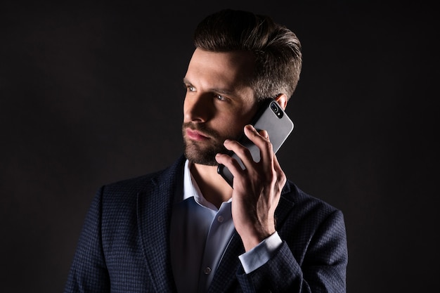 portret van zijn aantrekkelijke, stijlvolle, luxe kerel, werkgever die belt met een mobiel apparaat