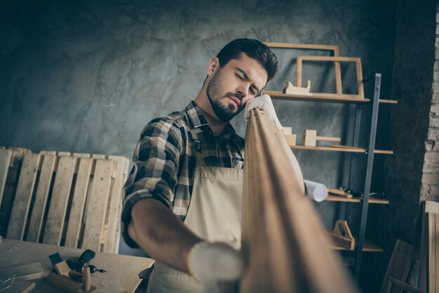 Portret van zijn hij mooi aantrekkelijk bebaarde ernstige geconcentreerde geconcentreerde ervaren geschoolde man specialist deskundige kijken gladheid plank op moderne industriële loft-stijl interieur controleren