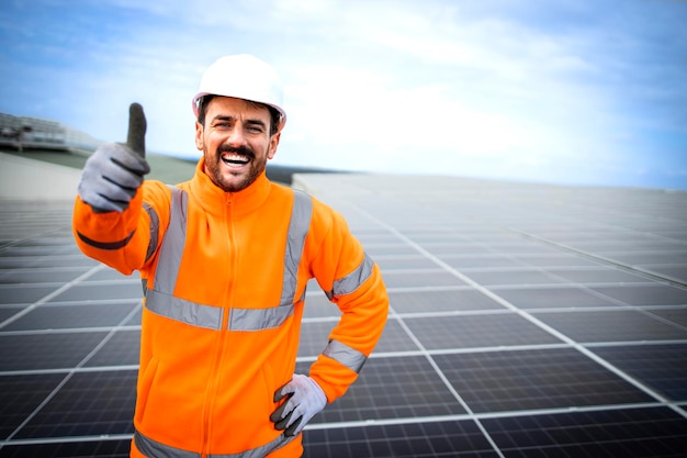 Portret van zonne-energie werknemer met duimen omhoog staande in zonne-energiecentrale