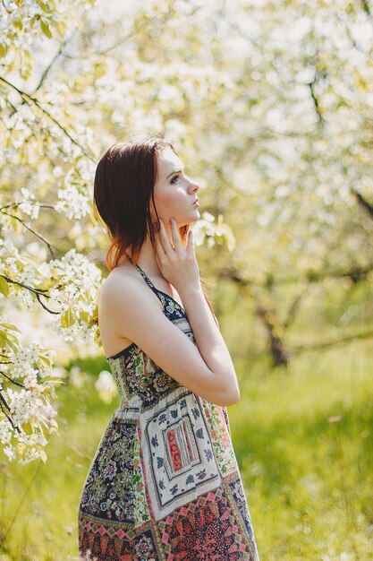 Portret van zorgeloze jonge vrouw in boho-stijl jurk in de lentetuin van de kersenbloesem.