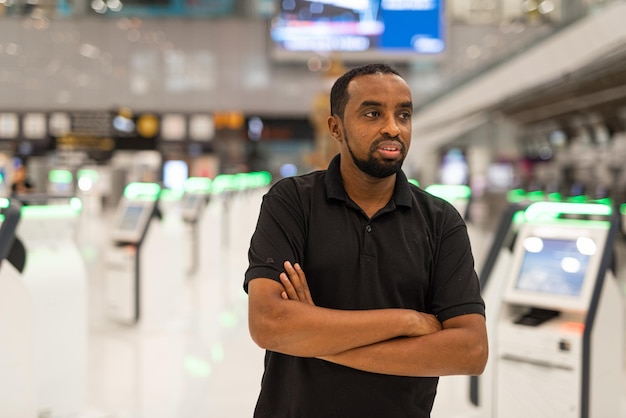 Portret van zwarte man klaar om te reizen op de luchthaventerminal, wachtend op de vlucht