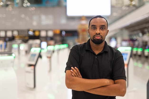 Portret van zwarte man klaar om te reizen op de luchthaventerminal, wachtend op de vlucht