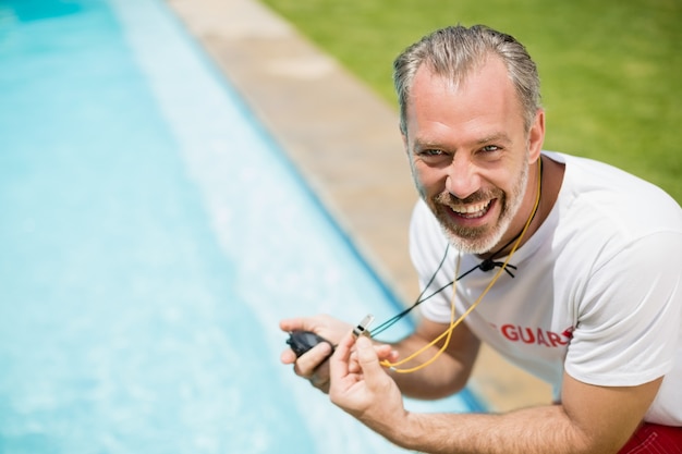 Portret van zwemmen coach stopwatch te houden in de buurt van het zwembad