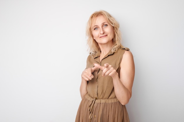 Portret volwassen vrouw kiest je geïsoleerd op witte studio achtergrond strekt haar handpalm uit naar de camera kom met me mee bij ons concept