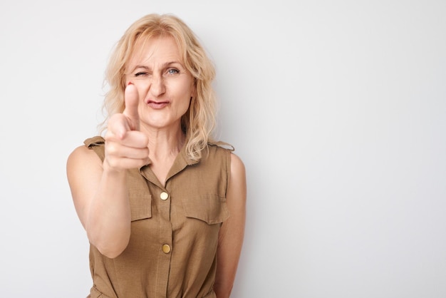 Portret volwassen vrouw kiest u geïsoleerd op witte studio achtergrond strekt haar handpalm naar de camera kom met me bij ons concept