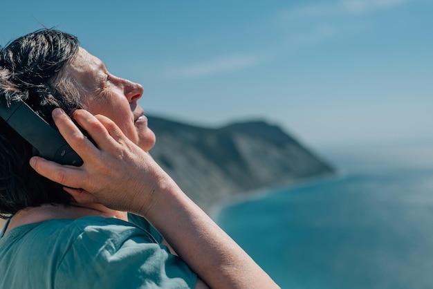 Portret volwassen vrouw luistert naar muziek in koptelefoon zomer bergen genieten van gepensioneerde