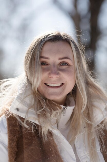 Portret Vreugdevolle jonge vrouw in warme winterkleding die plezier heeft in het winterwoud tussen de bomen