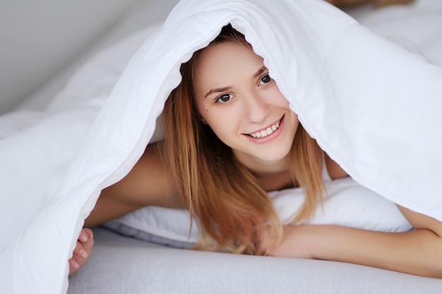 Foto portret vrij jong meisje op bed in moderne flat in de ochtend