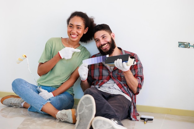 Portret Vrolijke paar jonge man en zwarte vrouw die lacht tijdens renovatie in nieuw appartement