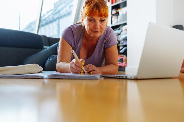 Portret vrouw liggend op parketvloer met laptop notebooks emoties op het gezicht