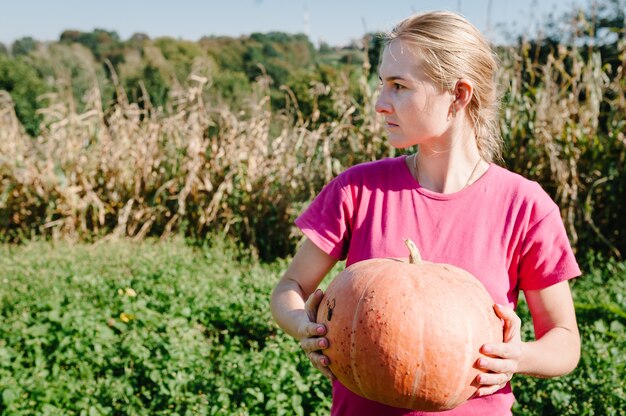 Portret vrouw met pompoen op veld