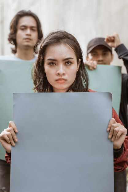 Foto portret vrouwelijke studenten demonstreren met hun vrienden die blanco papier houden