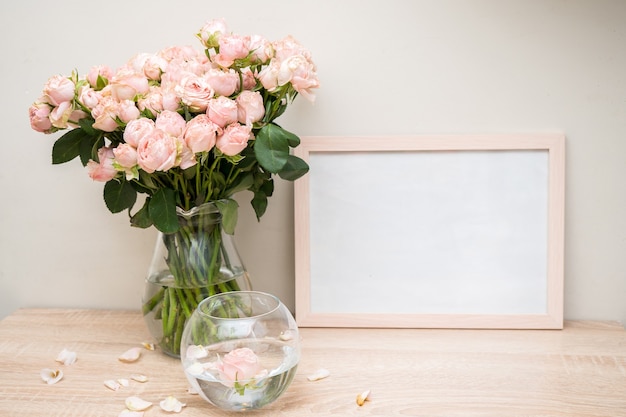 Portret wit fotolijstmodel op houten tafel moderne glazen vaas met rozen witte muur scandinavisch interieur