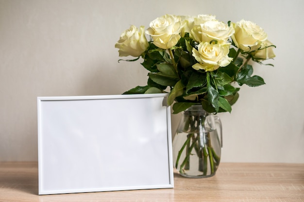 Portret wit frame mockup op houten tafel. Moderne vaas met rozen. Scandinavisch interieur. Hoge kwaliteit foto