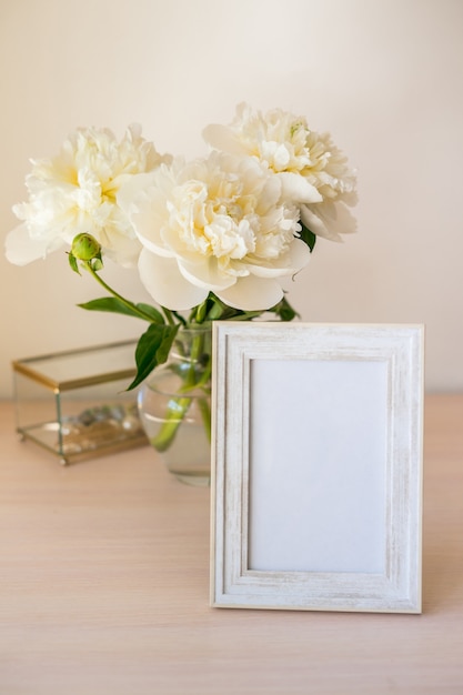 Portret witte fotolijst mockup op houten tafel Moderne glazen vaas met pioenroos Witte muur achtergrond Scandinavisch interieur Verticaal