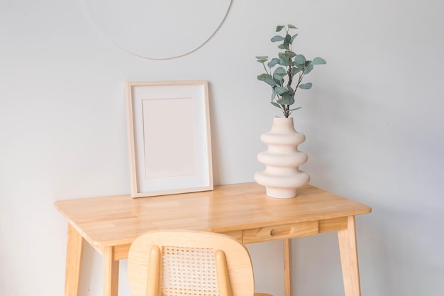 Portret witte fotolijst mockup op houten tafel. Moderne keramische vaas met eucalyptus.