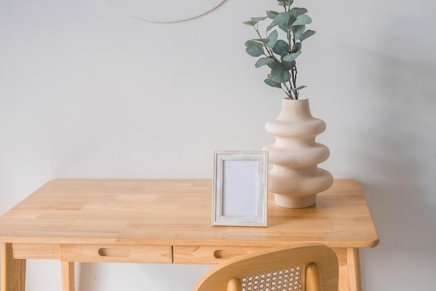 Portret witte fotolijst mockup op houten tafel. Moderne keramische vaas met eucalyptus.