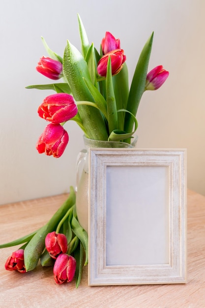 Portret witte fotolijst mockup op houten tafel Moderne vaas met tulpen Scandinavisch interieur