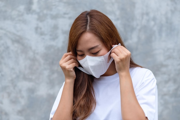 Portretbeeld van een Aziatische vrouw die een beschermend gezichtsmasker vasthoudt en opzet voor het concept Gezondheidszorg en Covid19