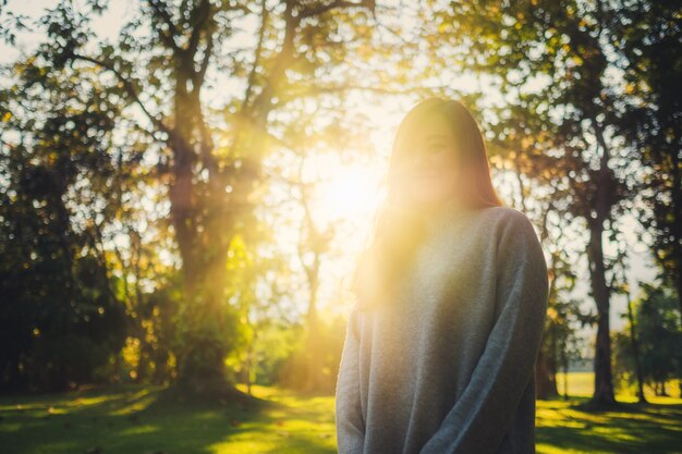 Portretbeeld van een mooie aziatische vrouw die voor zonsondergang in de natuur in het park staat