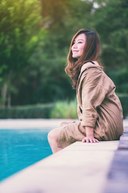 Portretbeeld van een mooie Aziatische vrouw genoot van het zitten bij het zwembad