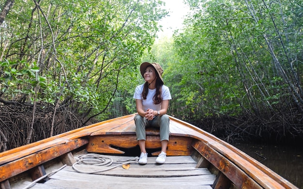 Portretbeeld van een mooie jonge aziatische vrouw die op een lange staartboot zit terwijl ze door het mangrovebos reist