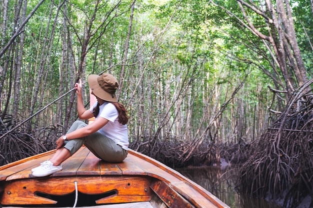 Portretbeeld van een mooie jonge aziatische vrouw die op een lange staartboot zit terwijl ze door het mangrovebos reist