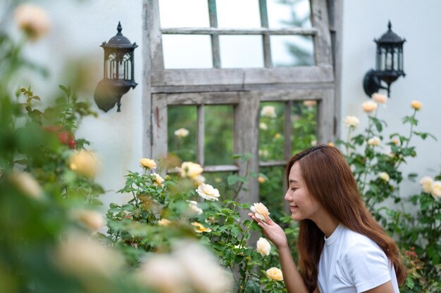 Portretbeeld van een mooie jonge Aziatische vrouw die rozenbloem in de tuin ruikt