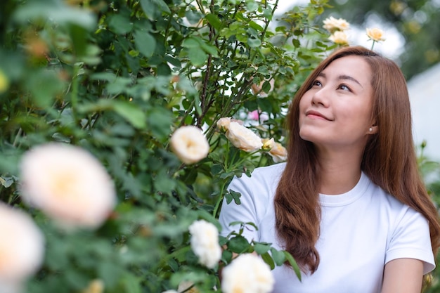 Portretbeeld van een mooie jonge Aziatische vrouw in de tuin van de rozenbloem