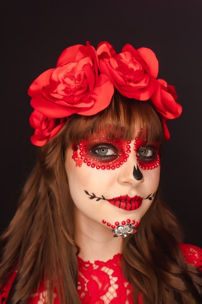 Portretdetail van het gezicht van een schattig jong meisje met day of the dead-make-up op zwarte achtergrond