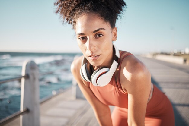 Portretfitness en moe met een zwarte hardloper op de promenade voor cardio- of duurtraining Hardlopen of ademhalen met een jonge vrouwelijke atleet die buiten aan zee traint