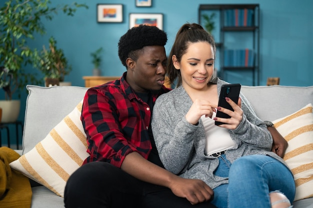 Portretfoto van de Amerikaanse jonge man en vrouw die thuis op de grijze bank zitten