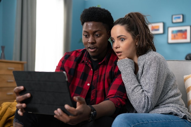 Portretfoto van een Amerikaanse jonge man en vrouw die thuis op een grijze bank zitten