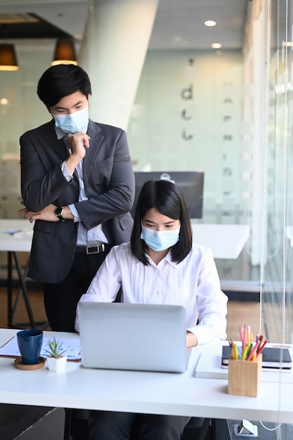 Portretondernemers die beschermend masker dragen die in modern bureau samenwerken.