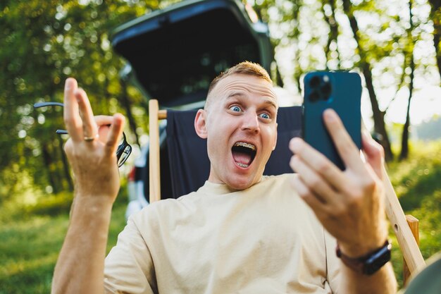 Portretten van een emotionele jongeman die aan de telefoon zit terwijl hij in het park zit Recreatie in de natuur werken op afstand Weekend in de natuur