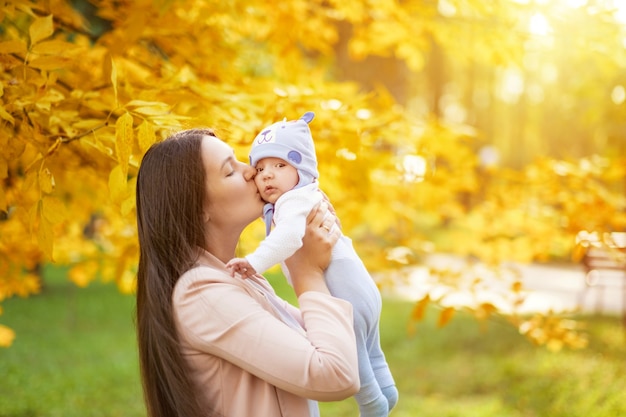 Portretten van moeder en baby in herfst park, moeder knuffels en kussen baby