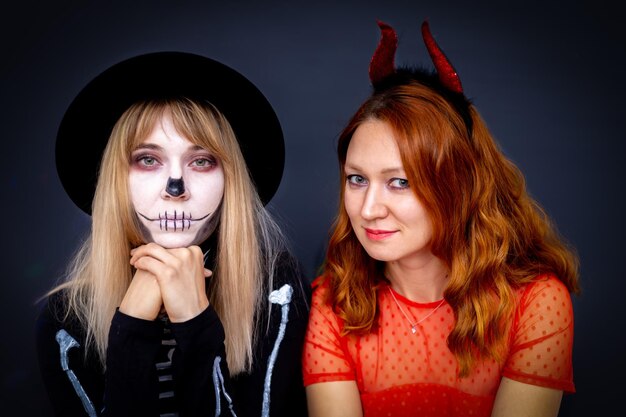 Portretten van twee jonge vrouwen gekleed als een duivel en een skelet op Halloween