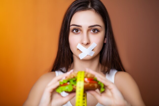 Portretvrouw wil een hamburger eten, maar zit vast in de mond van skochem, het concept van dieet.