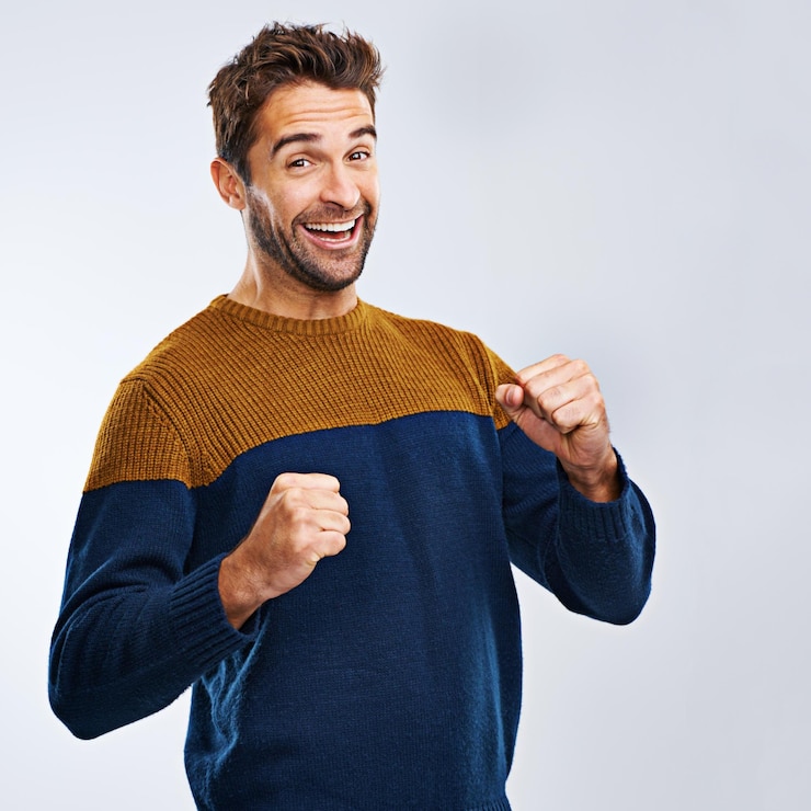 Foto portretwinnaar en man met energievuist en opwinding met man geïsoleerd tegen een studioachtergrond gezicht mannelijke persoon en model winnende doelen en geluk met overwinning wow en omg van vreugde