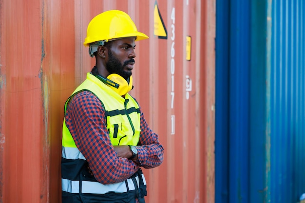 Portriat handsome male African American Industrial and factory Specialist Black man worker wearing yellow protective hard hat helmet working at container yard