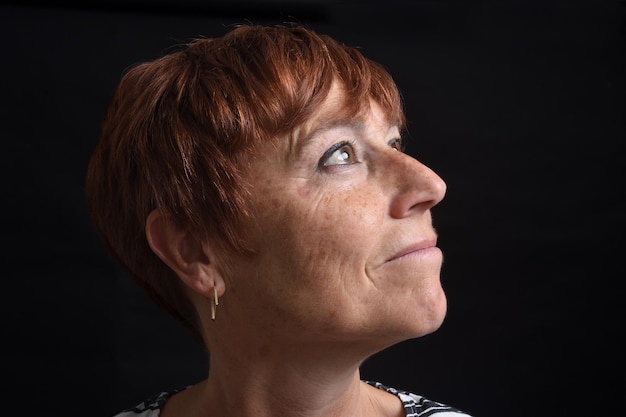 Portriat of a middleaged woman looking up on black background