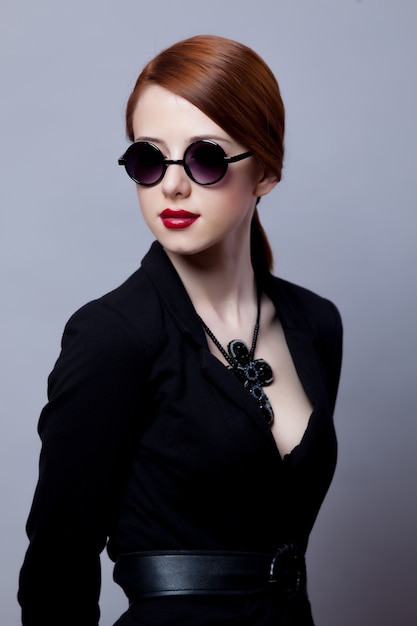 Portriat of style redhead girl in black clothes on grey