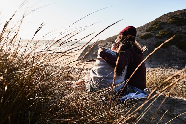 Portugal, Algarve, couple sitting on the beach at sunset